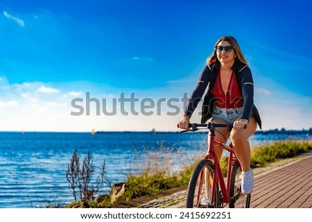Mid adult woman riding bicycle at seaside 