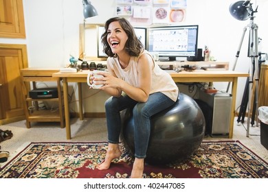 Mid Adult Woman Sitting On Yoga Ball, Holding Coffee Cup