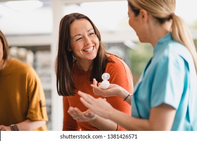 Mid adult woman speaking to a beauty product sales representative at a product party. She is sampling a beauty product.