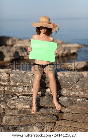 Mid Adult Woman in Swimsuit and Straw Hat on a beach holding over Breasts a Green Screen Frame - Copy Space Female Vacation Concept