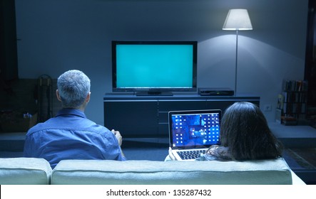 Mid Adults watching TV and PC blue tone