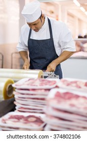 Mid Age Butcher Wrapping Meat In Butchery