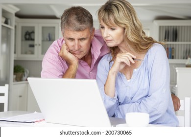 Mid Age Couple Working At Home On Laptop