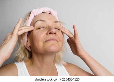 Mid Age Woman With Blond Hair Doing Face Self Massage And Yoga. Self Care For 50s Female 