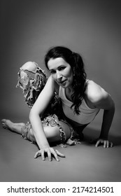 Mid Age Woman In Torn Jeans Sits On A Gray Background Monochrome