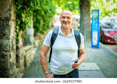 A mid aged man walking down the street in the city. Confident male wearing casual clothes and backpack.