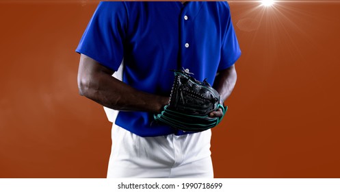 Mid section of african american male baseball pitcher against spot of light on orange background. sports tournament and competition concept - Powered by Shutterstock