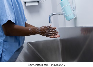 Mid Section Of African-american Male Surgeon Washing Hands In Sink At Hospital, Coronavirus Hand Washing For Clean Hands Hygiene Covid19 Spread Prevention.