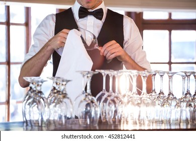 Mid section of bartender cleaning wine glass at bar counter - Powered by Shutterstock