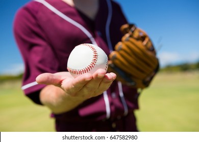 Mid section of baseball pitcher holding ball on palm at playing field - Powered by Shutterstock