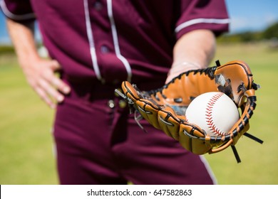 Mid section of baseball pitcher showing ball in glove at playing field - Powered by Shutterstock