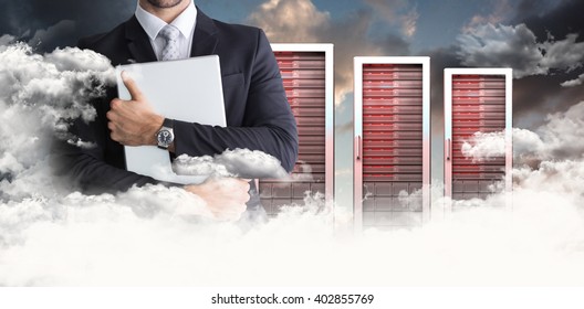 Mid section of businessman holding computer against blue and orange sky with clouds - Powered by Shutterstock