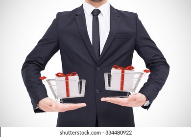 Mid section of a businessman holding something against trolley full of gifts - Powered by Shutterstock