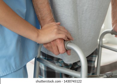 Mid section of Caucasian female doctor helping active senior man to walk with walker at home - Shutterstock ID 1430745122