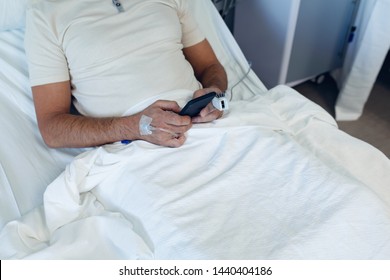 Mid Section Of Caucasian Male Patient Using Mobile Phone In The Ward At Hospital