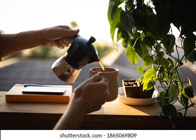 Mid section of a Caucasian woman spending time at home self isolating and social distancing in quarantine lockdown during coronavirus covid 19 epidemic, pouring coffee from a moka pot.  - Powered by Shutterstock