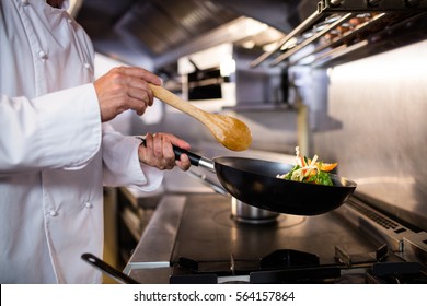 Mid section of chef preparing food in the kitchen of a restaurant - Powered by Shutterstock