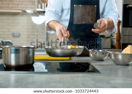 Mid section of chef preparing food in the kitchen of a restaurant
