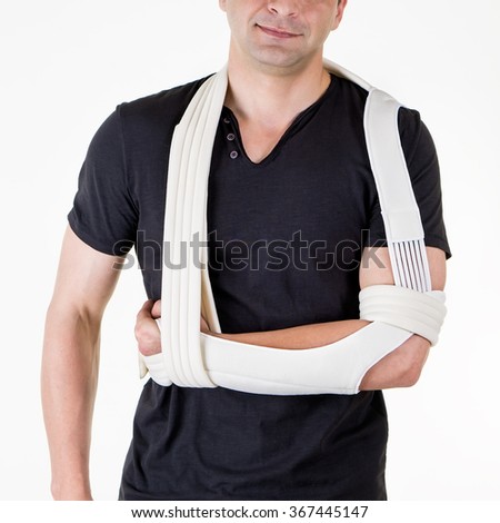 Mid Section Close Up of Man with Arm Supported in Modern Cast Sling and Standing in Studio with White Background