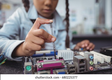 Mid section of elementary girl assembling circuit board on desk at electronics lab - Powered by Shutterstock