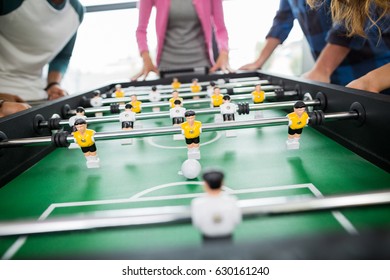 Mid section of executives playing table football in office