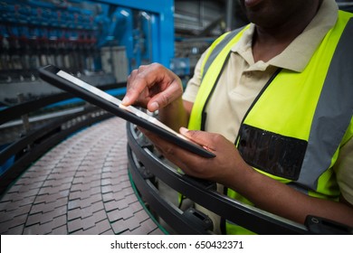 Mid Section Of Factory Worker Using Digital Tablet In The Factory