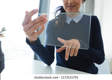Mid section of female executive using glass digital tablet at desk in office