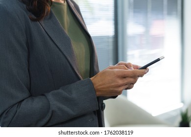 Mid section of female executive using mobile phone in office