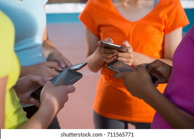 Mid section of female players using mobile phones in volleyball court - Powered by Shutterstock