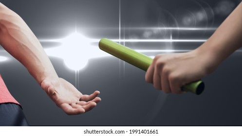 Mid section of hand passing a baton against spot of light on grey background. sports competition and tournament concept
