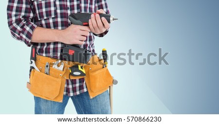 Mid section of handy man with tool belt holding a drill against blue background