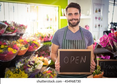 Mid section of male florist holding open sign on slate at his flower shop - Powered by Shutterstock