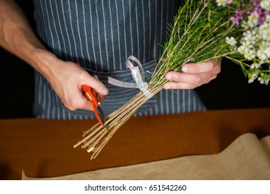 Mid section of male florist trimming flower stem in flower shop - Powered by Shutterstock