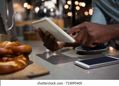 Mid section of man using digital tablet in restaurant - Powered by Shutterstock