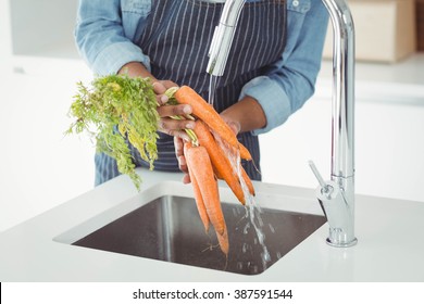 Mid section of man washing carrots in the kitchen - Powered by Shutterstock