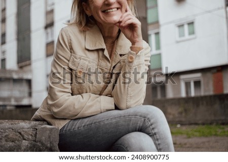 mid section of a mature woman's body with emotions on her face while sitting outside