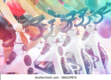 Mid Section Of People Working Out At Spinning Class Against Abstract Background