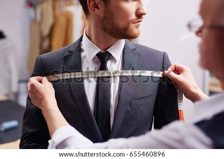 Mid section portrait of tailor fitting bespoke suit to model