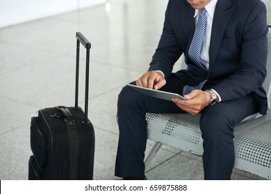 Mid Section Portrait Of Unrecognizable Businessman Using Digital Tablet While Waiting In Airport With Suitcase