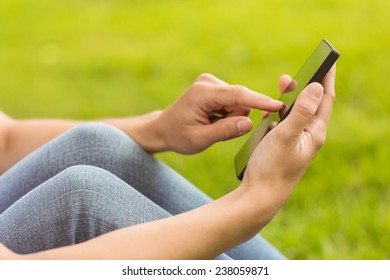 Mid section of a pretty redhead texting in park