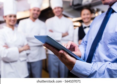 Mid section of restaurant manager using digital tablet in commercial kitchen - Powered by Shutterstock