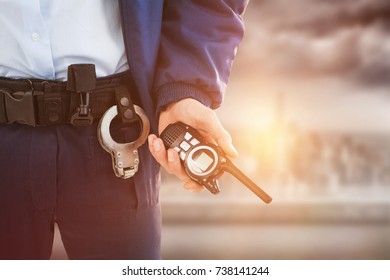 Mid section of security officer holding walkie talkie against balcony overlooking city - Powered by Shutterstock