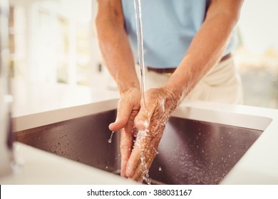 Mid section of senior man washing hands in the kitchen - Powered by Shutterstock