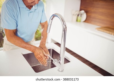 Mid section of senior man washing hands in the kitchen - Powered by Shutterstock