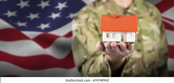 Mid section of soldier holding model house against focus on usa flag - Powered by Shutterstock