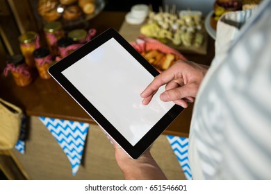 Mid section of staff using digital tablet in grocery shop