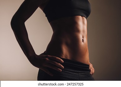 Mid section of strong young woman torso with her hands on hips. Abs of female  athlete in sportswear.