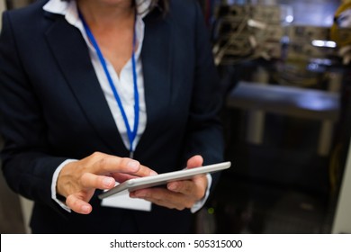 Mid section of technician using digital tablet in server room