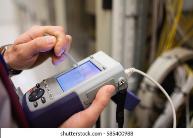 Mid section of technician using digital cable analyzer in server room - Powered by Shutterstock