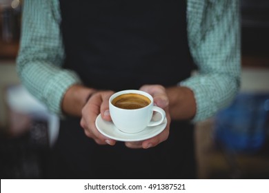 Mittelteil des Kellners, der eine Tasse Kaffee im Cafe hält – Stockfoto